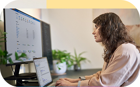 A person working on a laptop and looking at multiple monitors.