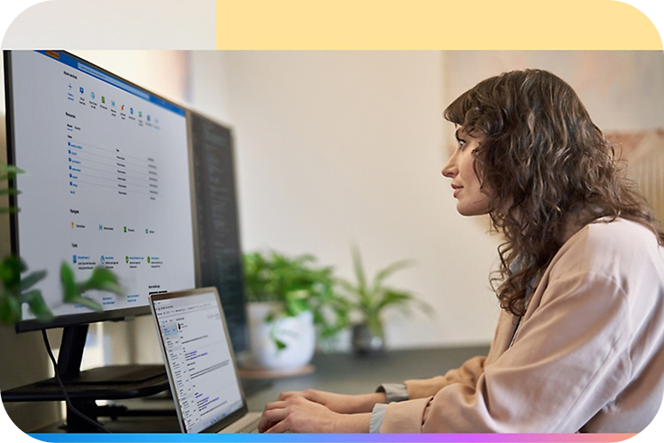 A person working on a laptop and looking at multiple monitors.