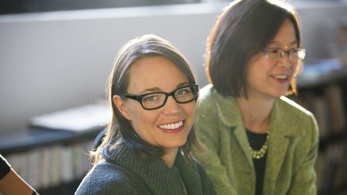 Two women smile in a  professional environment