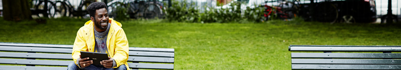A man uses his tablet while sitting on a bench