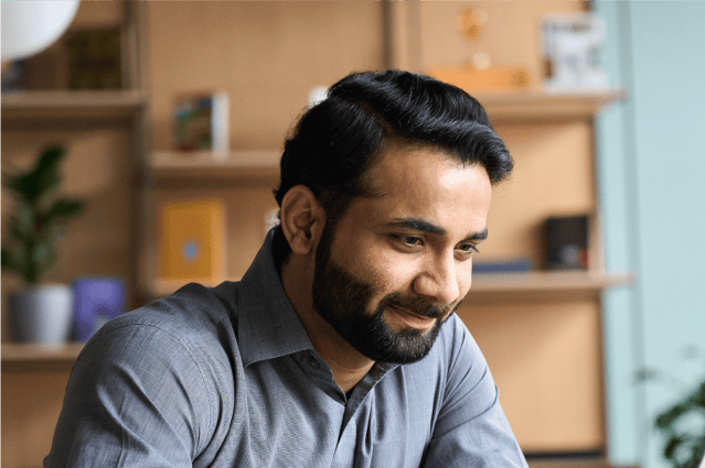 A smiling person looking at a laptop in an office