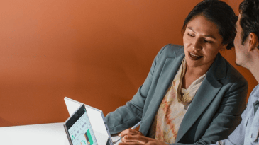 Two people with laptops talking