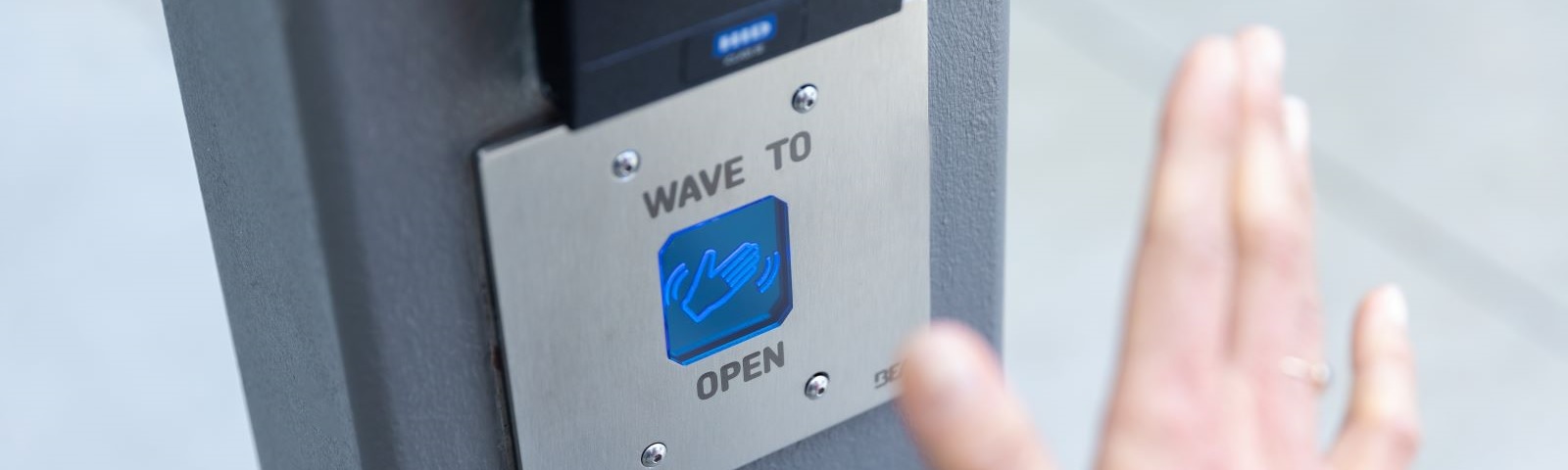 Close up of an employee using a motion sensor to open a building door