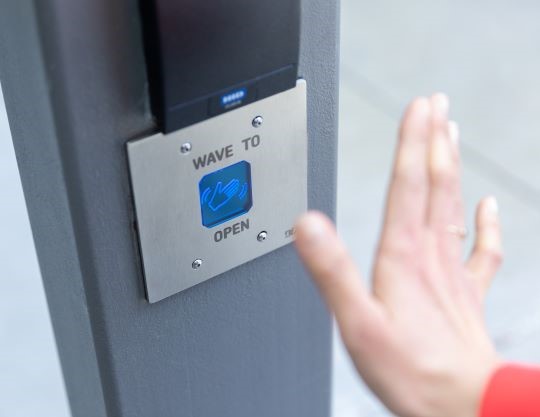 Close up of an employee using a motion sensor to open a building door