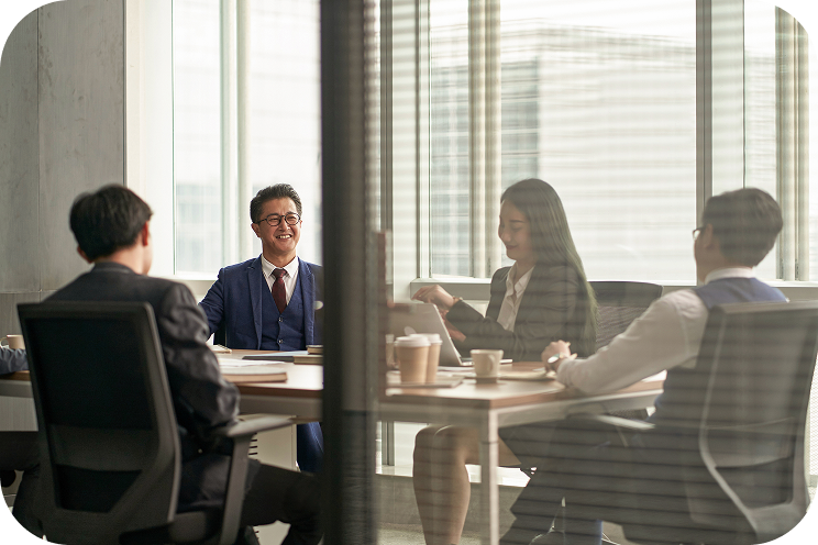 Four people sit in a conference room.