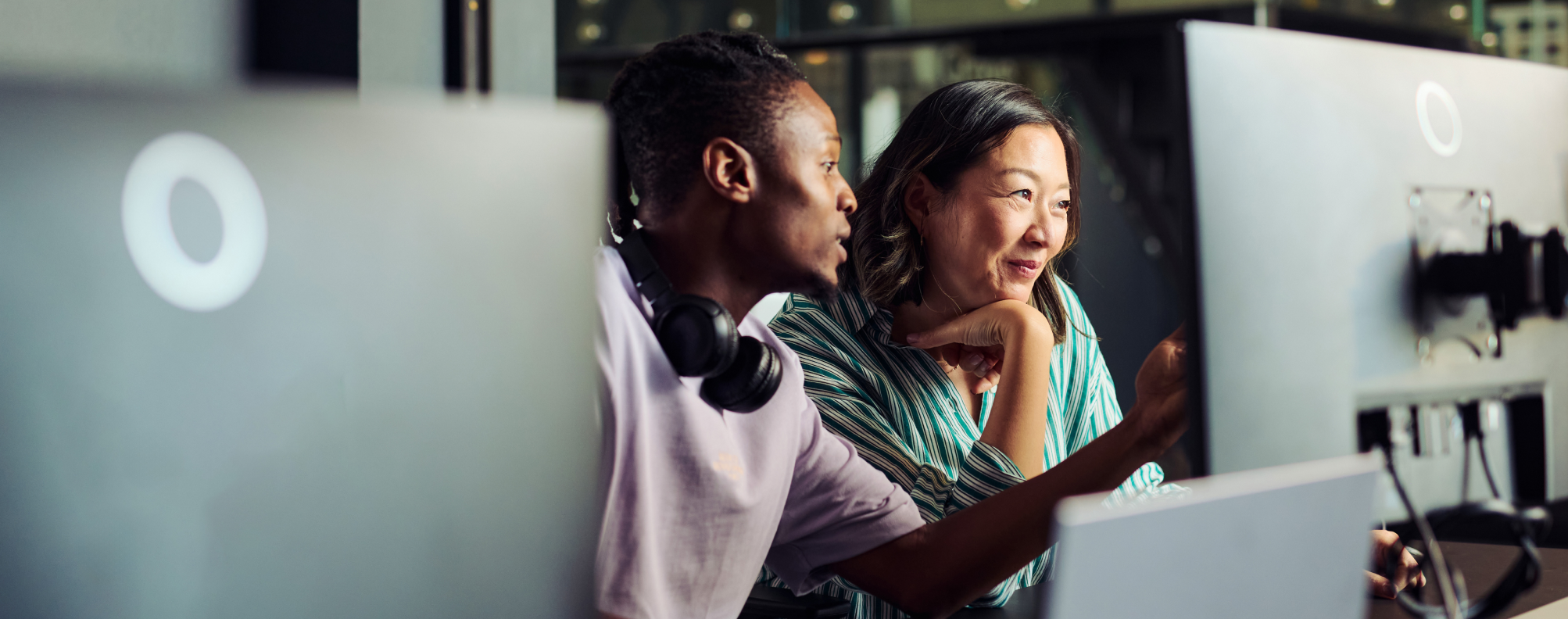 Two professionals collaborating at a desk, focused on a computer screen in a modern office setting.