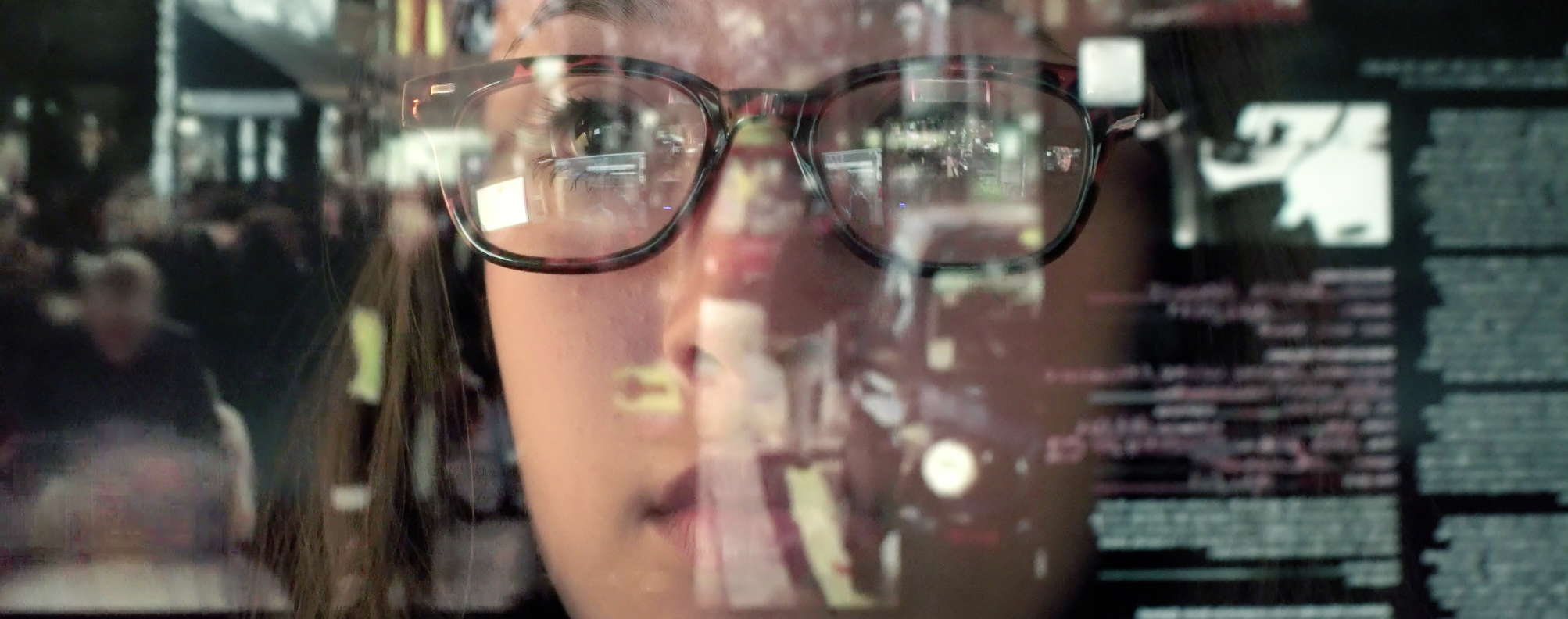 reflection of a person's face and a computer screen in a window