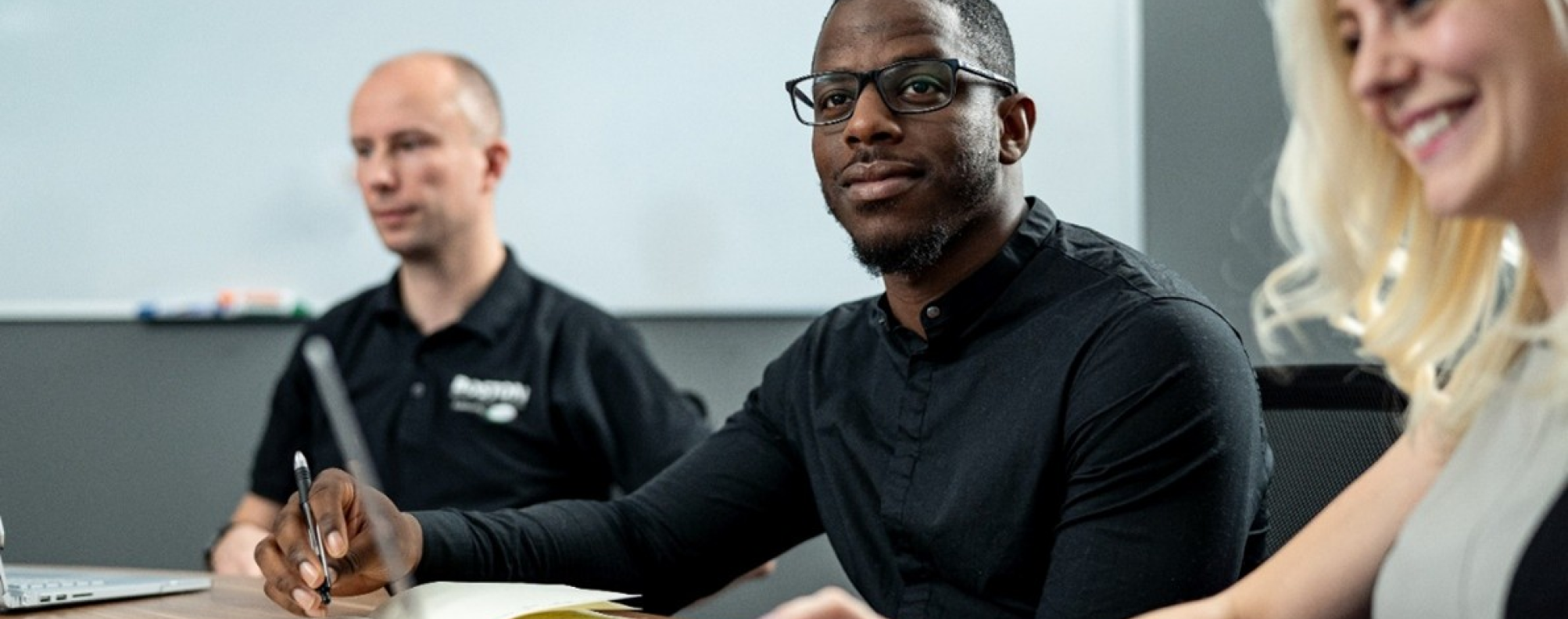 Three people sitting at a table in a conference room.