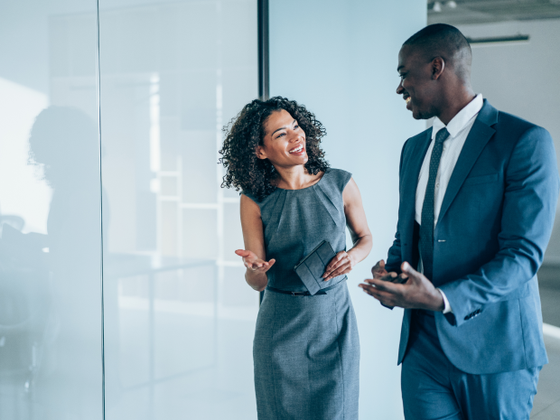 Two people in an office building laughing together.