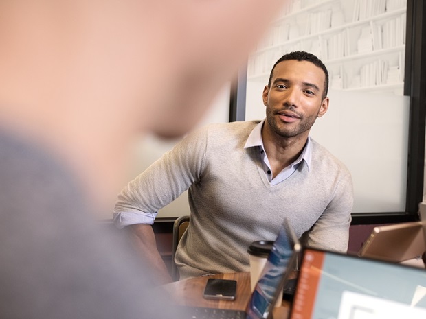 Professional man in modern conference room looking at colleague who is out of frame