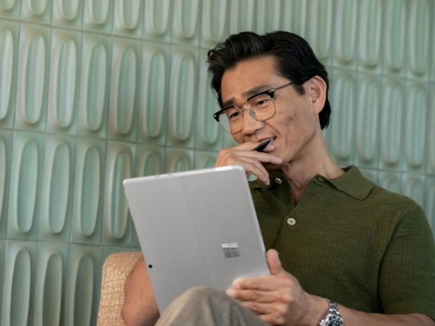 A person smiles thoughtfully while using a Microsoft Surface.