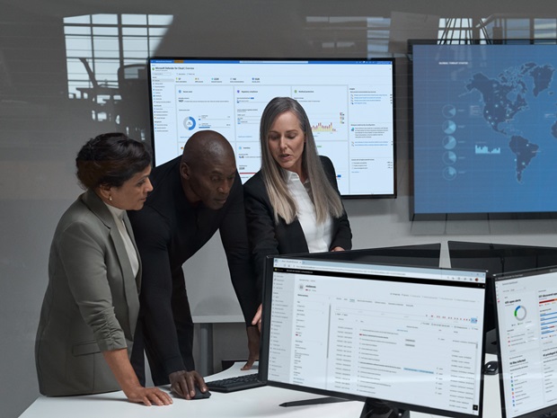 Three members of a cybersecurity team gathered around a computer.