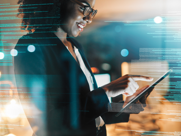 A business person using a tablet device in a modern office surrounded by digital data visualizations