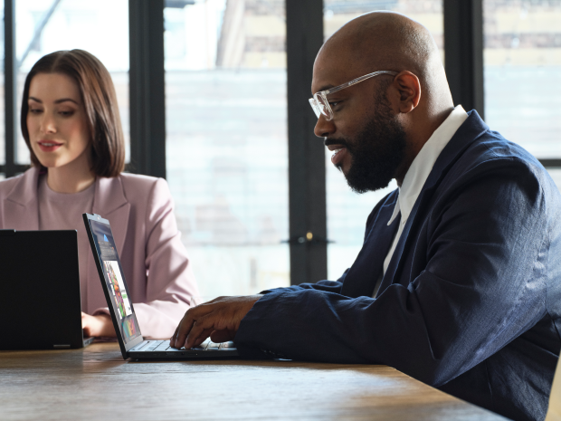 Two people sitting in an office working on computers.