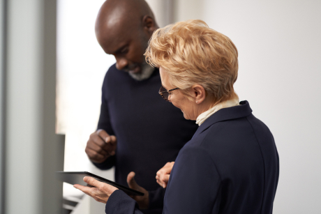 Two people standing looking at a tablet