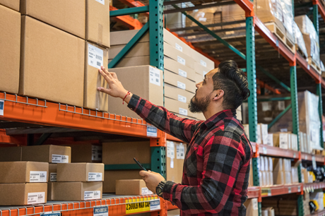 A warehouse worker reads a label on a box