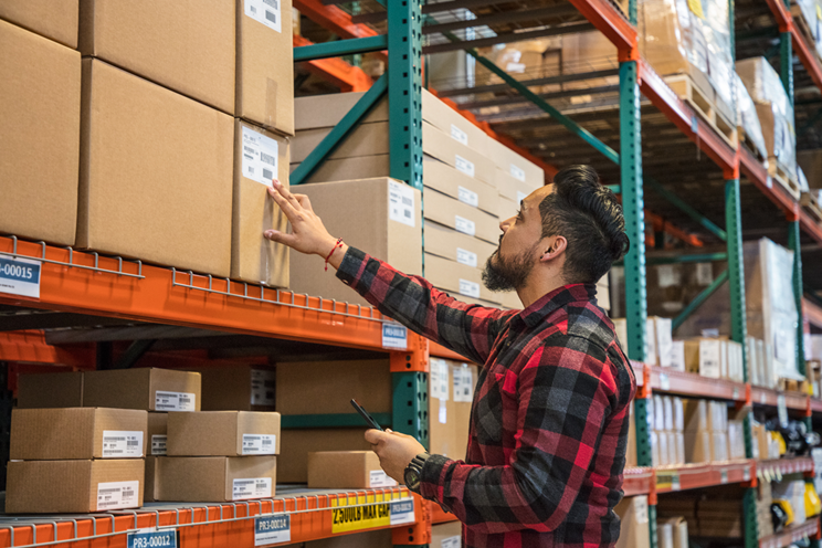 A warehouse worker reads a label on a box