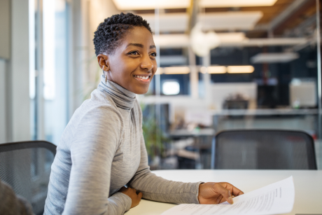 Person seated in an office smiling.