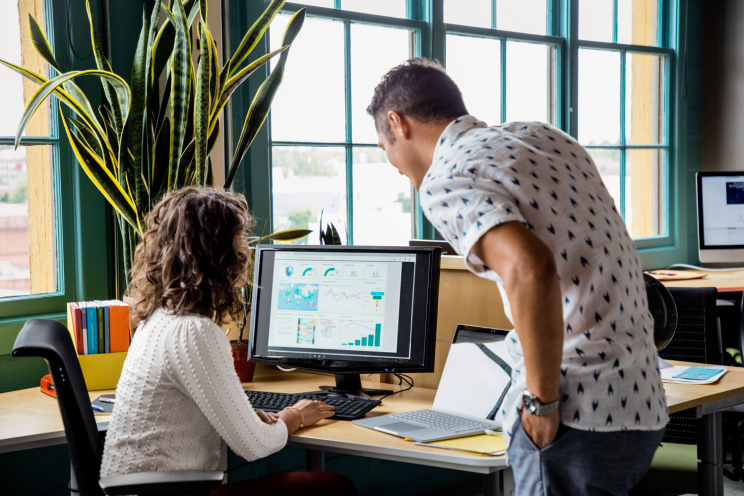 Two colleagues look at a computer monitor