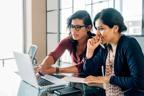 Two people working on a laptop together.