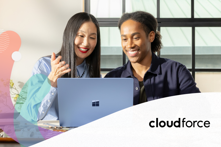 Two people working on a laptop and smiling.