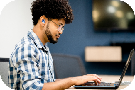 Person working on a laptop wearing headphones.