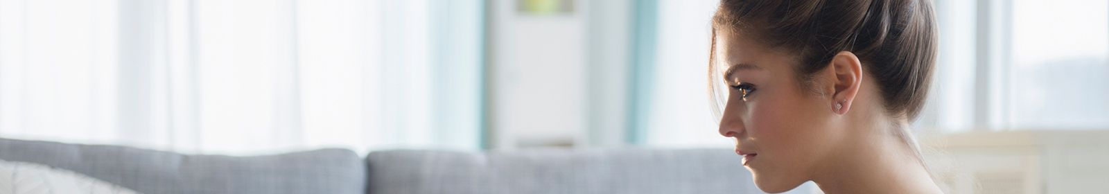 A woman holds a piece of paper and works on a laptop at a coffee table