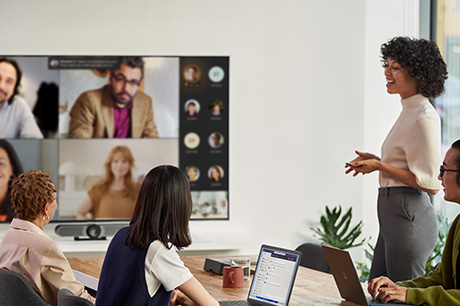 A woman presents to colleagues in person and via Teams