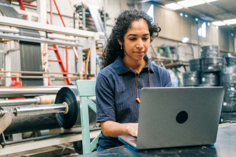 A person using a laptop at a desk in a factory