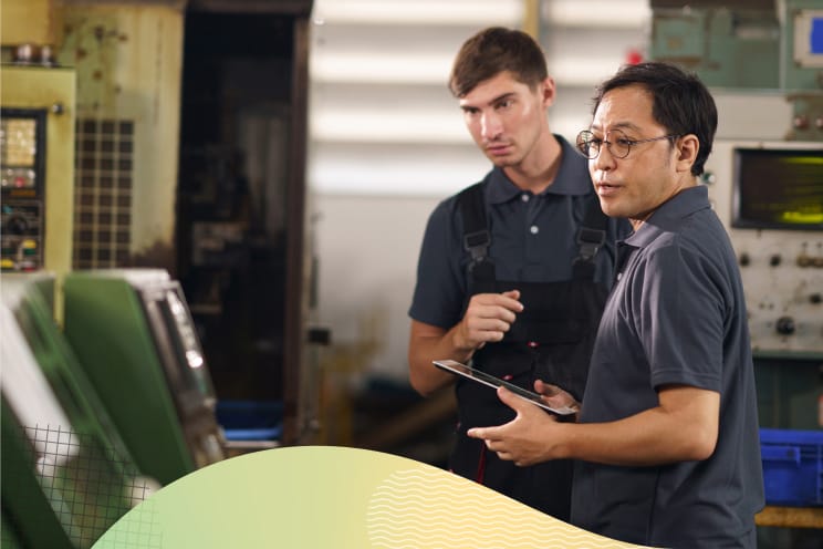 Two people in a factory observing machinery