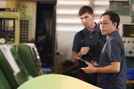 Two people in a factory observing machinery