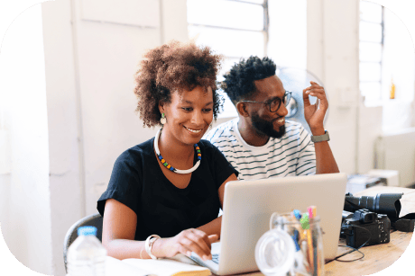 Due persone che sorridono mentre lavorano a un laptop