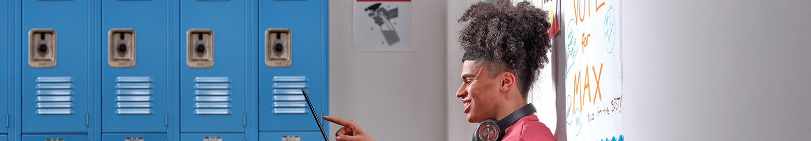 Profile of a student sitting on a hallway floor holding a laptop