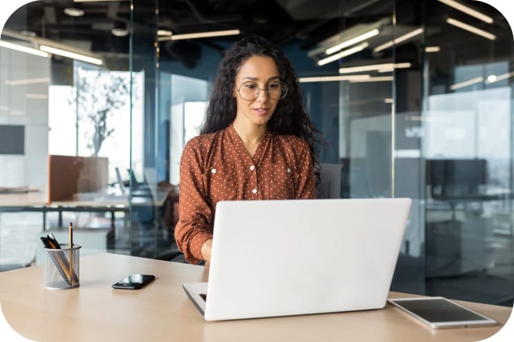 A person at a desk looking at a laptop