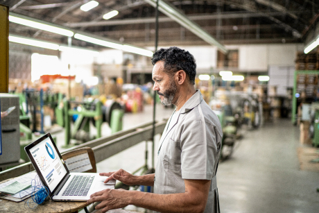 Person in a manufacturing space looking at a laptop