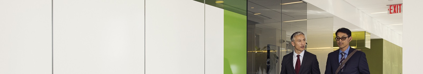 Two traveling businessmen walk through an office