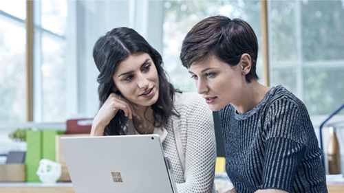Two coworkers looking at a Surface laptop