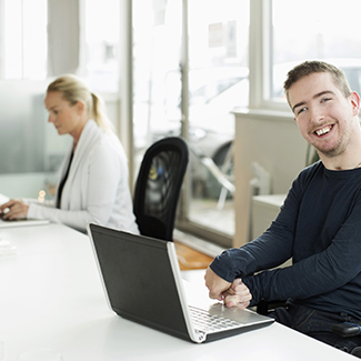 Portrait of smiling businessman using laptop in office