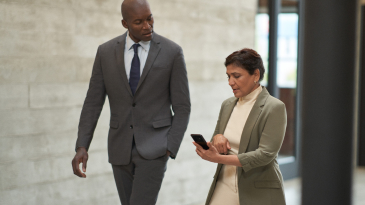 Two people walking look at smart phone