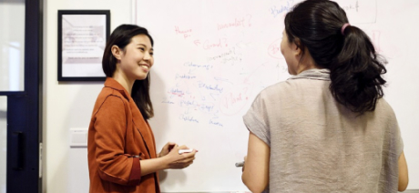 Two coworkers meeting in front of whiteboard