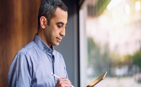 Person working on a tablet with a stylus.