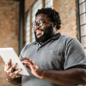 A person smiles while using a tablet