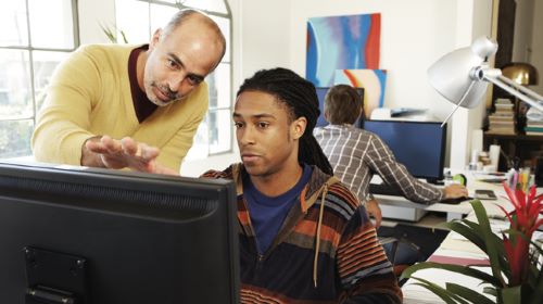 Two men looking at a computer with Microsoft Office