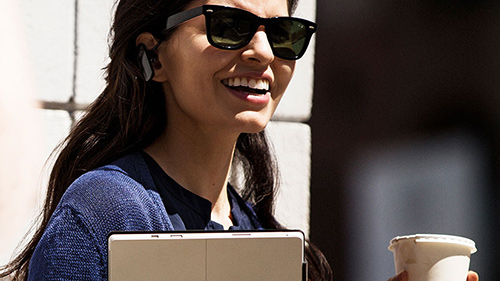 Woman smiling with drink and tablet in hands