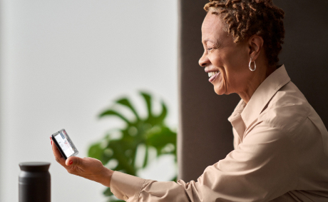 A smiling woman holding her mobile phone in her hands while having a video call