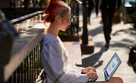 A woman working on her laptop at a park