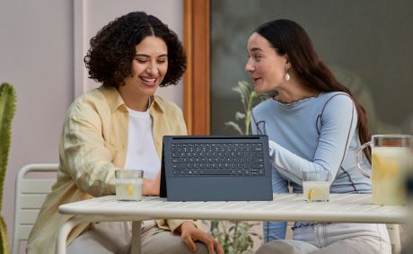 Two smiling women having lemonades in front of a laptop