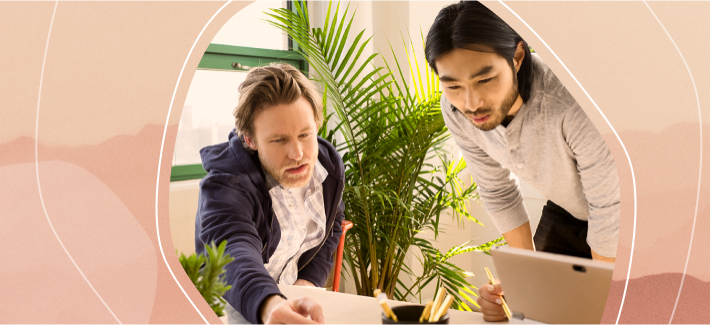 Two people having a discussion in a conference room with plants in the background