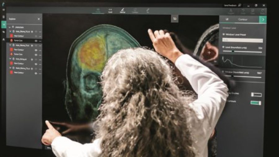 Person using a large touch screen display showing images of an MRI brain scan