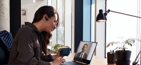 Woman drinking a cup of coffee on a video conference call